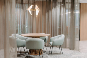 Collaborative space with curtain screening to allow private meeting space. Upholstered meeting chairs with timber table and feature bird pendant light from Amonson Lighting.