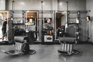 Barber chair with LED mirror and feature pipework structure to create shelving and structure. Industrial concrete look wall with pipework details.