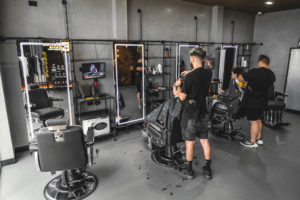 Barber chair with LED mirror and feature pipework structure to create shelving and structure. Industrial concrete look wall with pipework details.