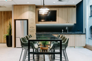 Break out area with Fat shack vintage Printmaker Rod pendant light, Vorsen Coco kitchen stool and bespoke glass table with shelf for pot plants. Timber kitchen with blackboard splashback and black marble look top.