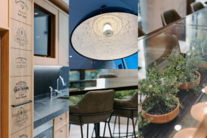 Printed logo's on timber cupboard front. Light fixture with surprising interior. Vorsen Coco kitchen stools in vintage green. Potted greenery under glass table top.