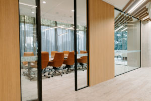 Boardroom entrance with timber panel wall and ceiling panels. Leather boardroom chairs and feature linear pendants. Curtain to filter light in boardroom.