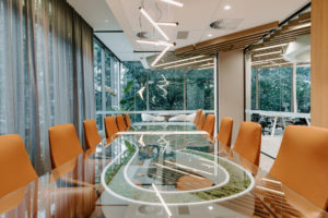 Boardroom table created with preserved moss feature element. Glass table top with Preserved moss river through centre. Leather boardroom chairs from FDB Commercial. Feature pendant lighting over table.