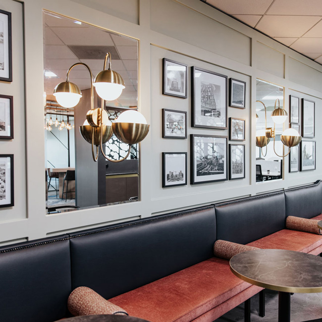 Break out banquette seating with a traditional theme. Wall mouldings framing artwork and mirrored panels. Wall light in front of mirror panel.